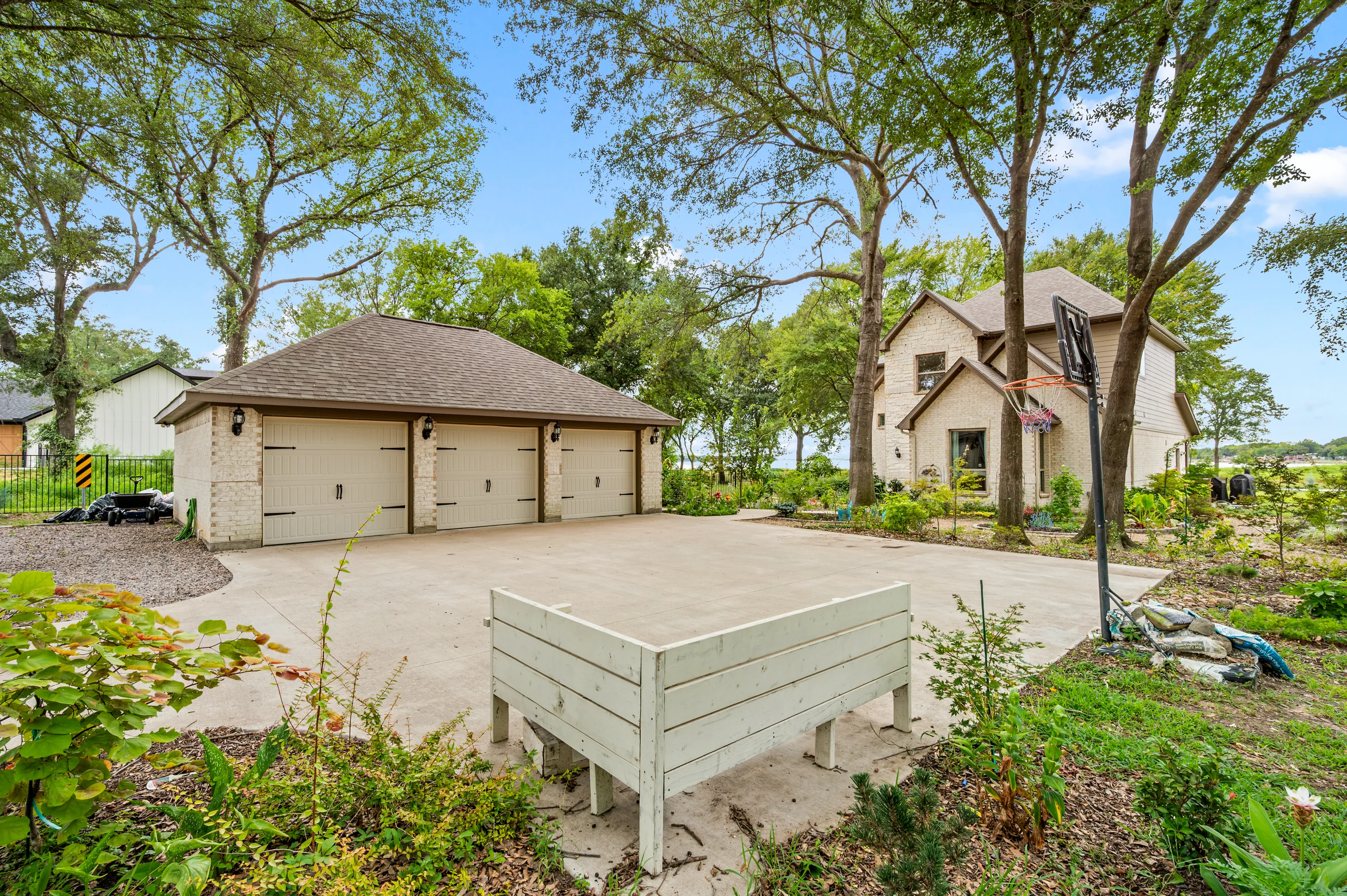Three-car garage and expanded driveway framed by gardens