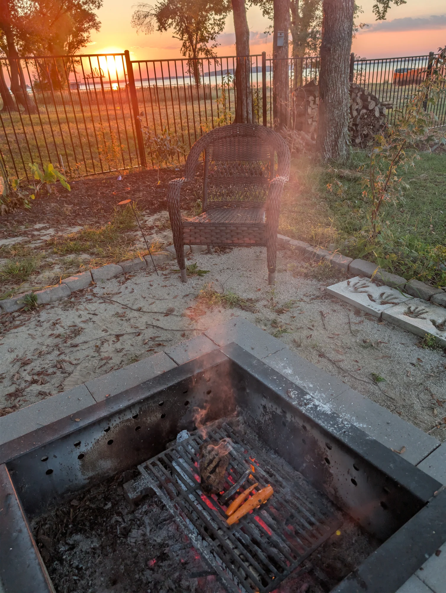 Campfire near Cedar Creek Lake as the sun sets through the trees